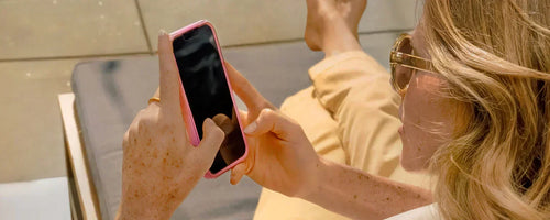 Woman holding her iPhone in a protective pink OtterBox iPhone case