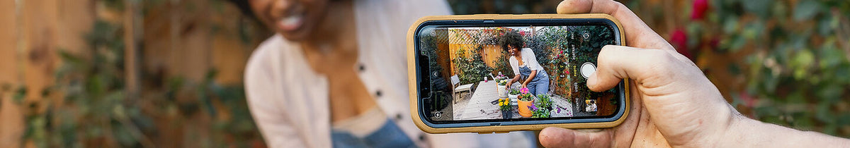Woman taking a photo on her iPhone with OtterBox protective phone case and OtterBox Glass screen protector
