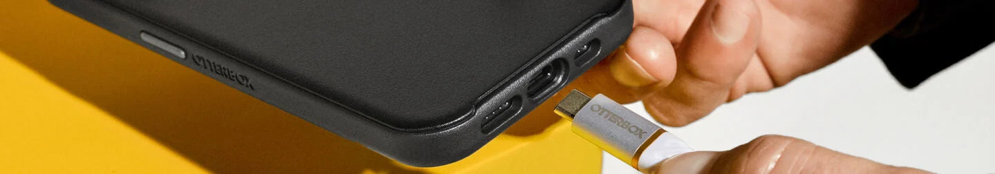 Man plugging OtterBox charging cable into iPhone charging port