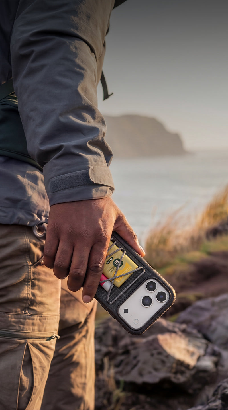 Person holding a phone with a rugged case in a natural setting