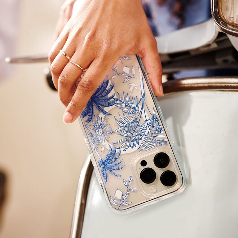 Hand holding a phone with a floral design case on a scooter.