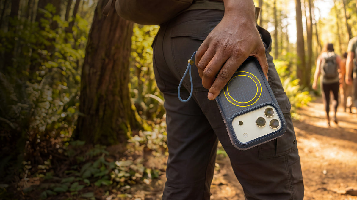 Person holding a blue sole series otterbox case in an outdoor hikinh background