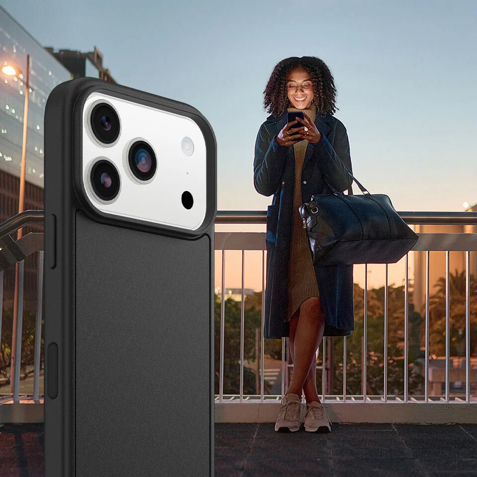 Person holding a phone with a large phone case in front, standing on a balcony.