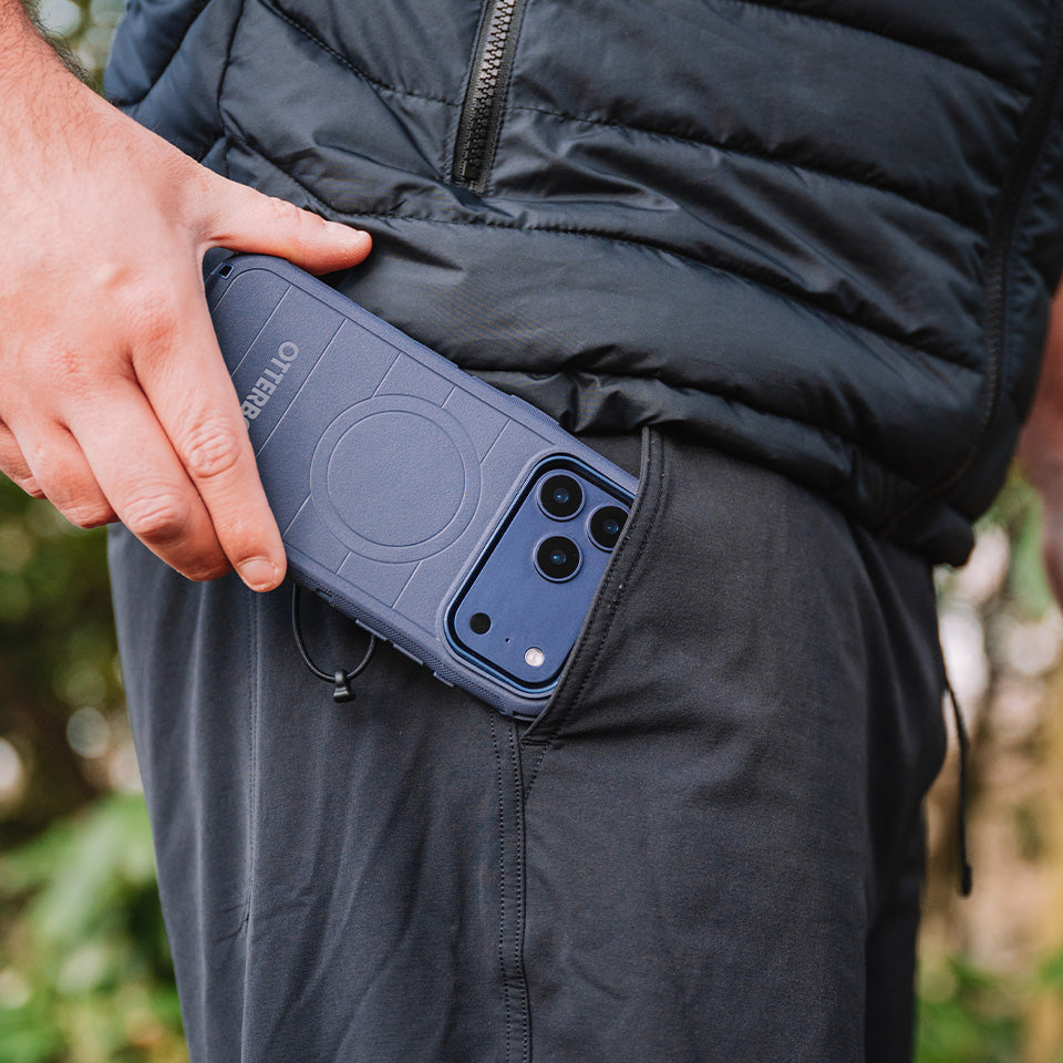 Person wearing a black puffer jacket and holding a blue defender phone case 