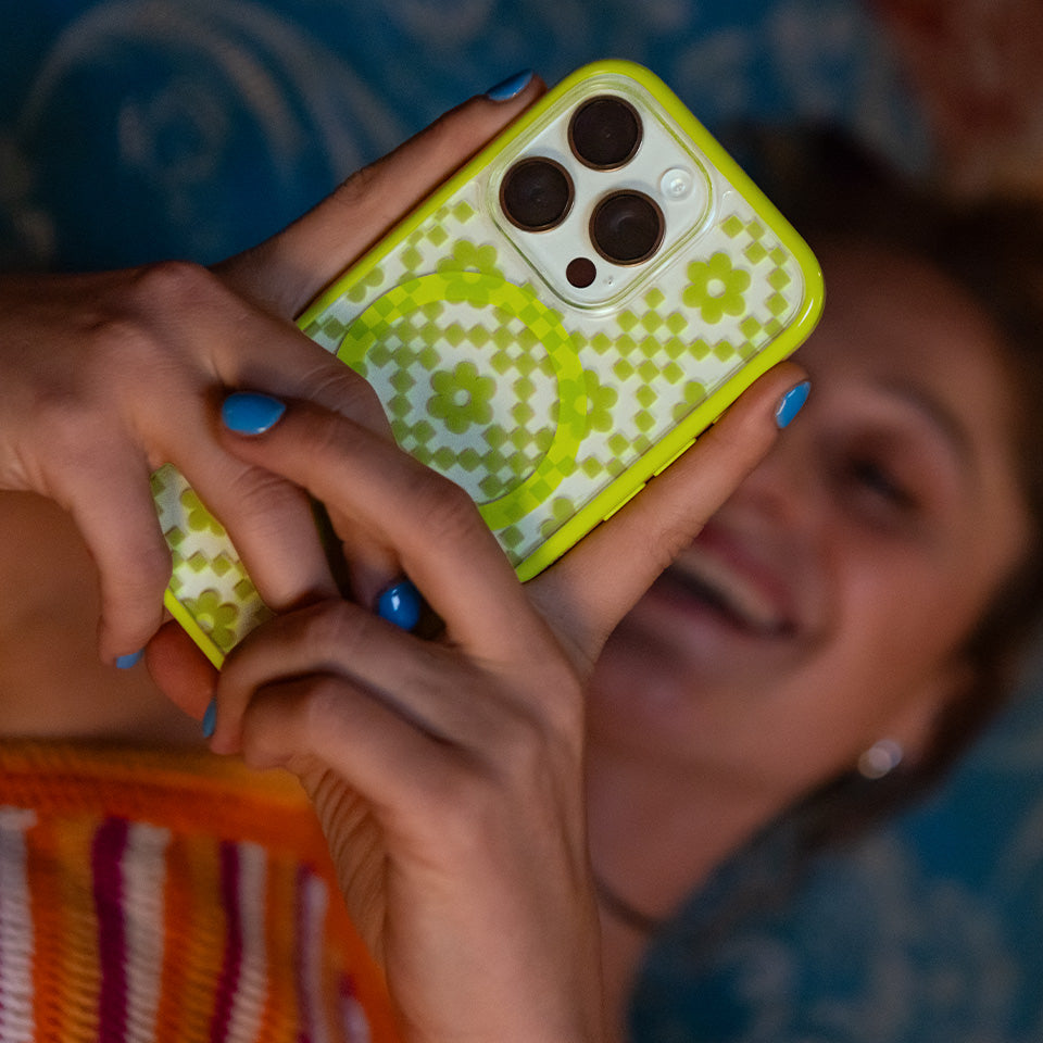 Person holding a phone with a green floral case, blurred background