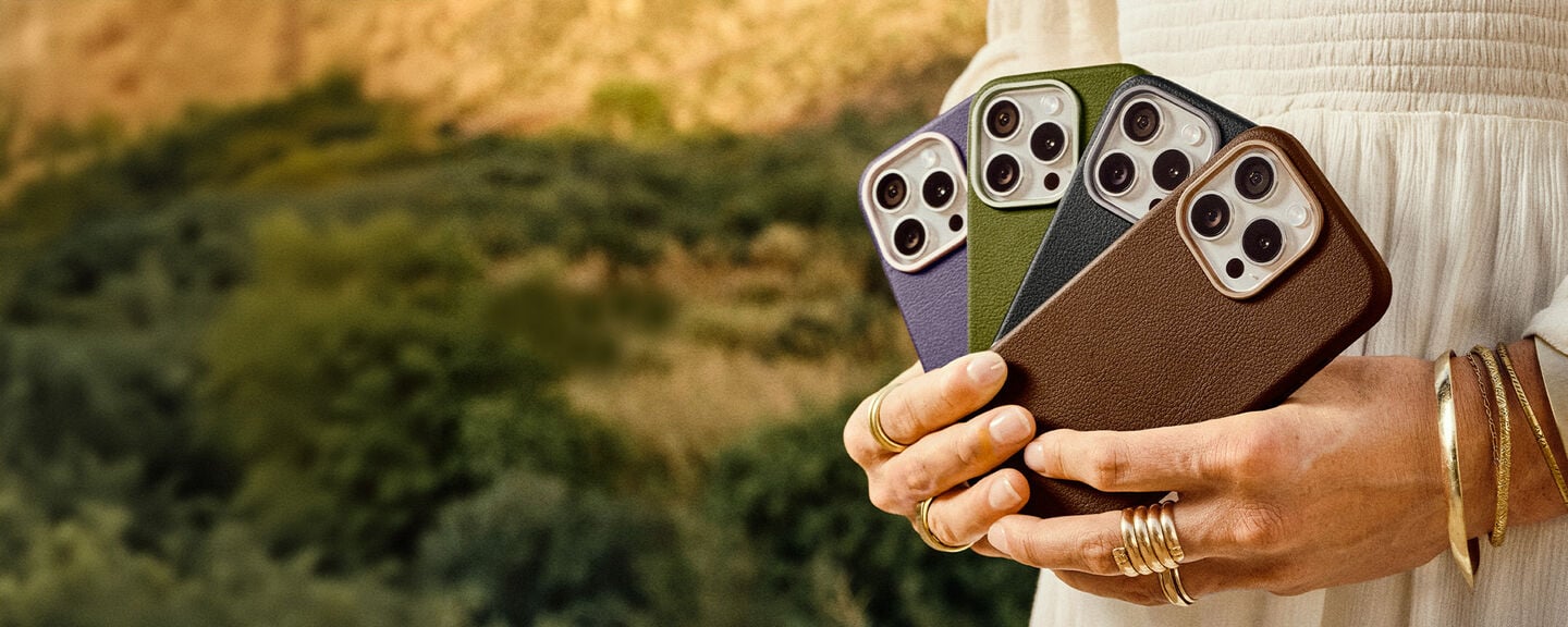 Person holding three different colored cactus leather phone cases against a natural background