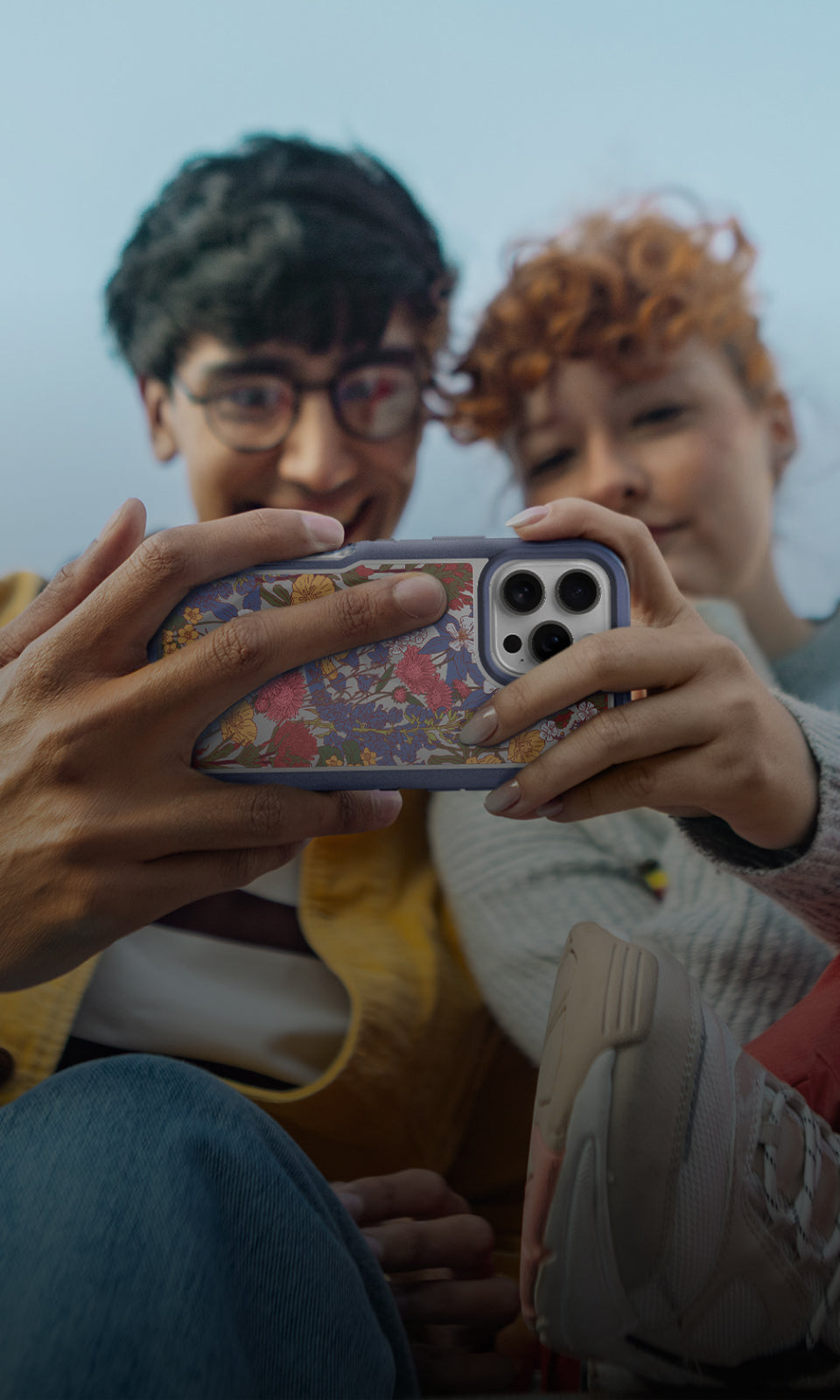 Two people holding a phone looking at the screen with a floral phone case