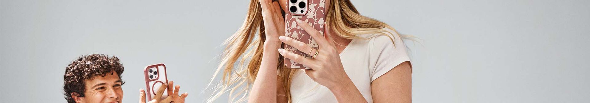 Man and woman holding iPhone 16 in colorful cases | OtterBox